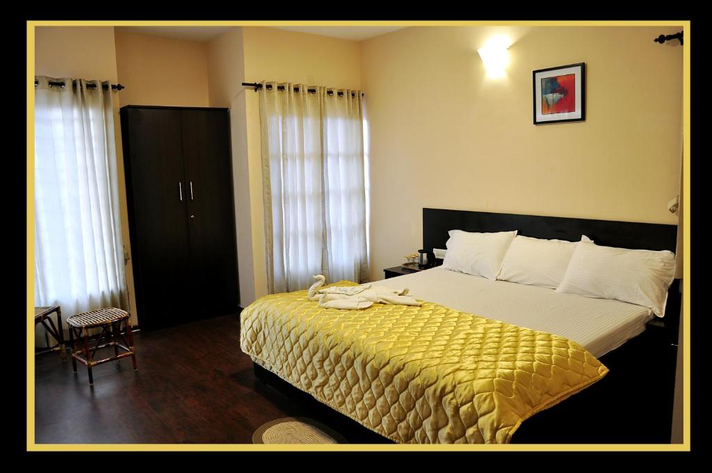 a bedroom with a large bed with a yellow blanket at The Hill Side in Ooty