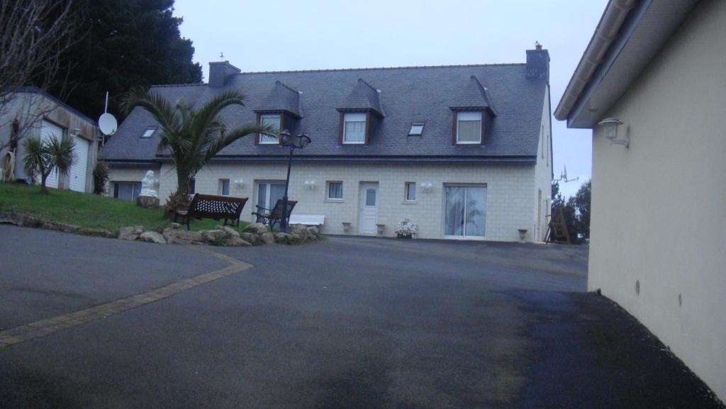 une grande maison blanche avec un banc devant elle dans l'établissement Chez JoMi, à Trébeurden