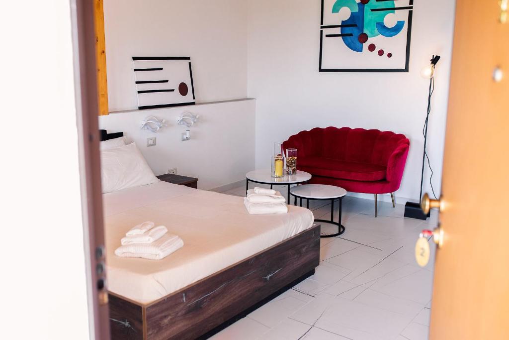 a bedroom with a bed and a red chair at Limora' Tenuta Millaci in Mazzarino