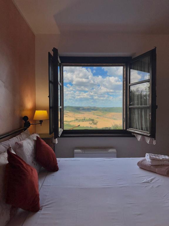 蒙特普齐亚诺AFFITTACAMERE Casale Le Civette的一间带大床和大窗户的卧室
