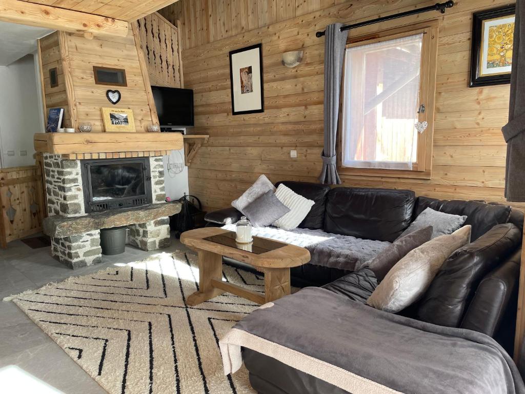 a living room with a leather couch and a fireplace at Chalet Soleil, magnifique triplex sur les pistes in La Rosière
