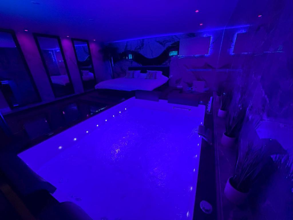 a dark room with a swimming pool with purple lights at La Suite Genève Gaillard - Jacuzzi Privé & Séjour Luxe in Gaillard