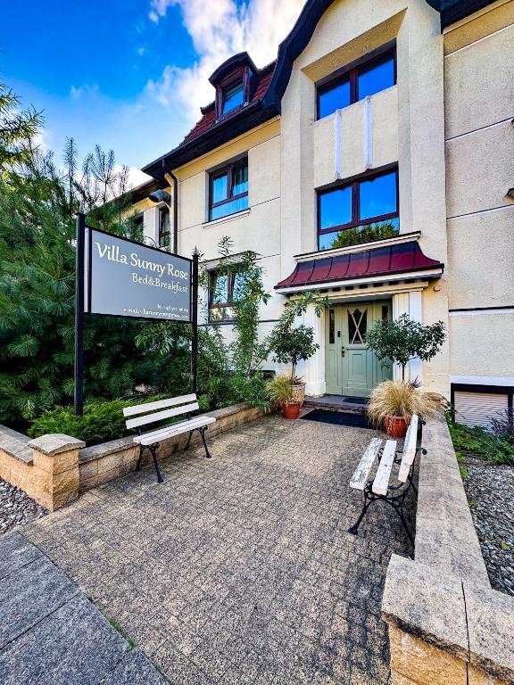 a sign in front of a building with two benches at VILLA SUNNY ROSE Bed & Breakfast in Świnoujście