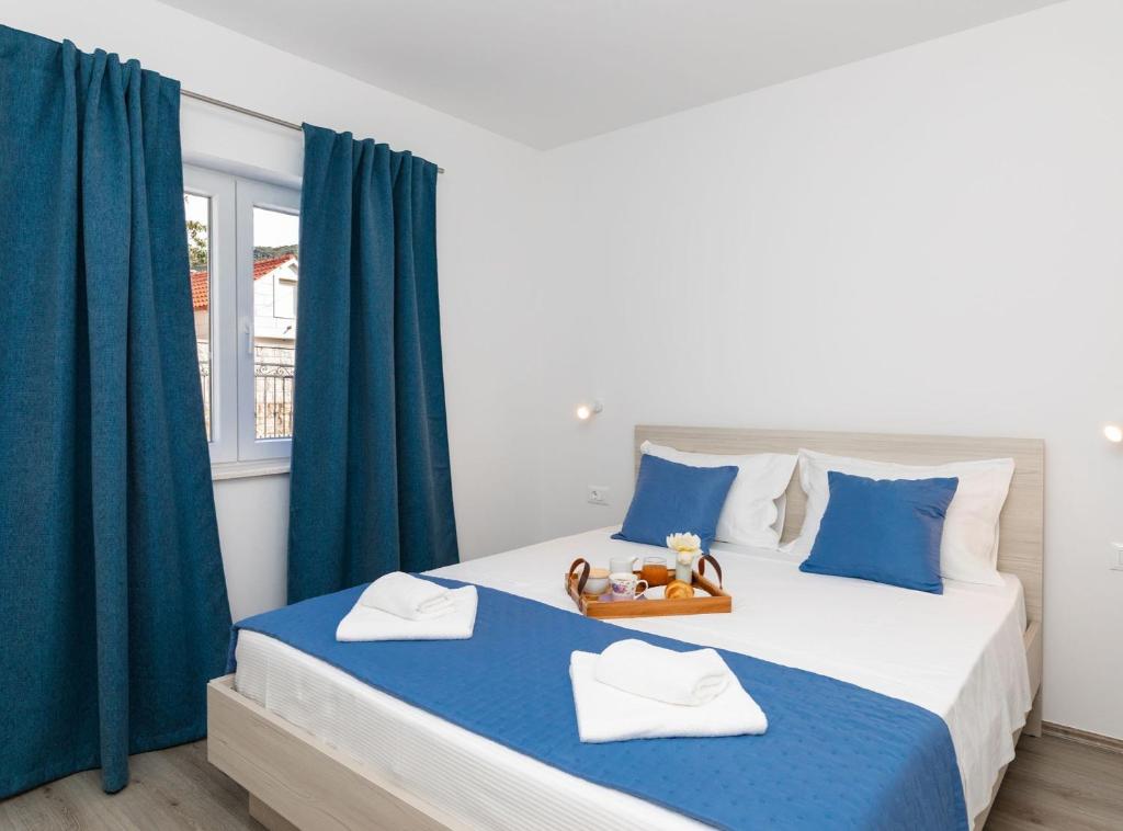 a bedroom with two beds with blue curtains and a window at Apartment Kurte in Nerežišća