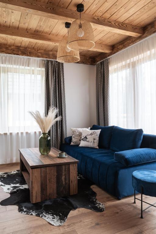 a living room with a blue couch and a coffee table at Domki Miętusówka in Dzianisz