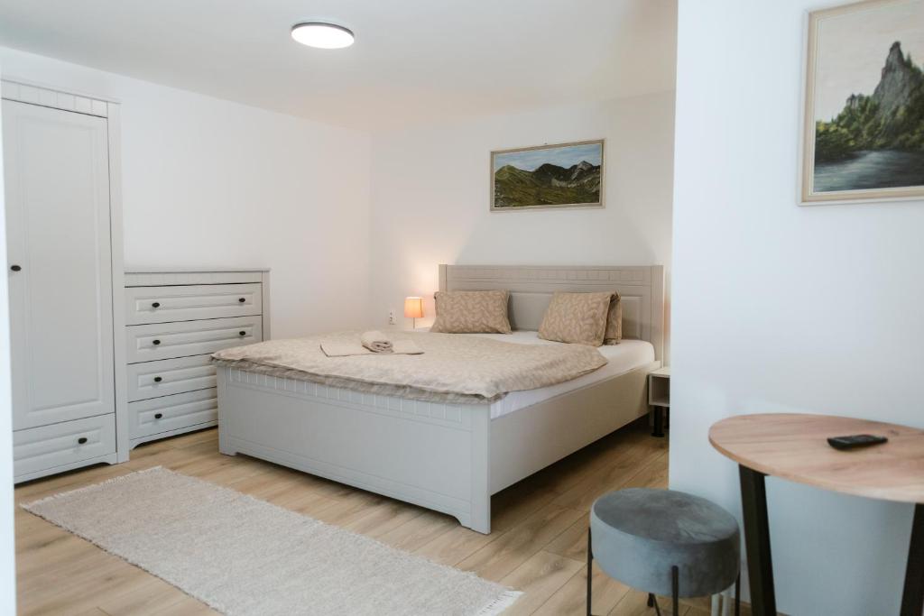 a white bedroom with a bed and a table at Penzión Hubert in Zuberec