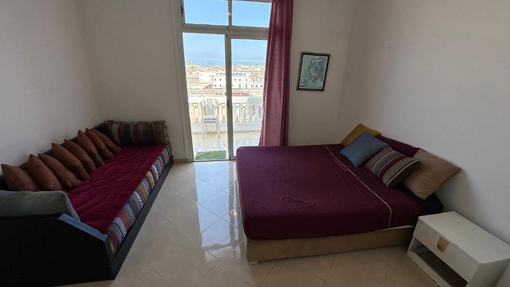 a bed and a couch in a room with a window at Chambre privée au cœur de Rabat in Rabat