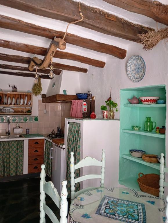 a kitchen with a table and chairs and a refrigerator at La Maestra in Trevélez