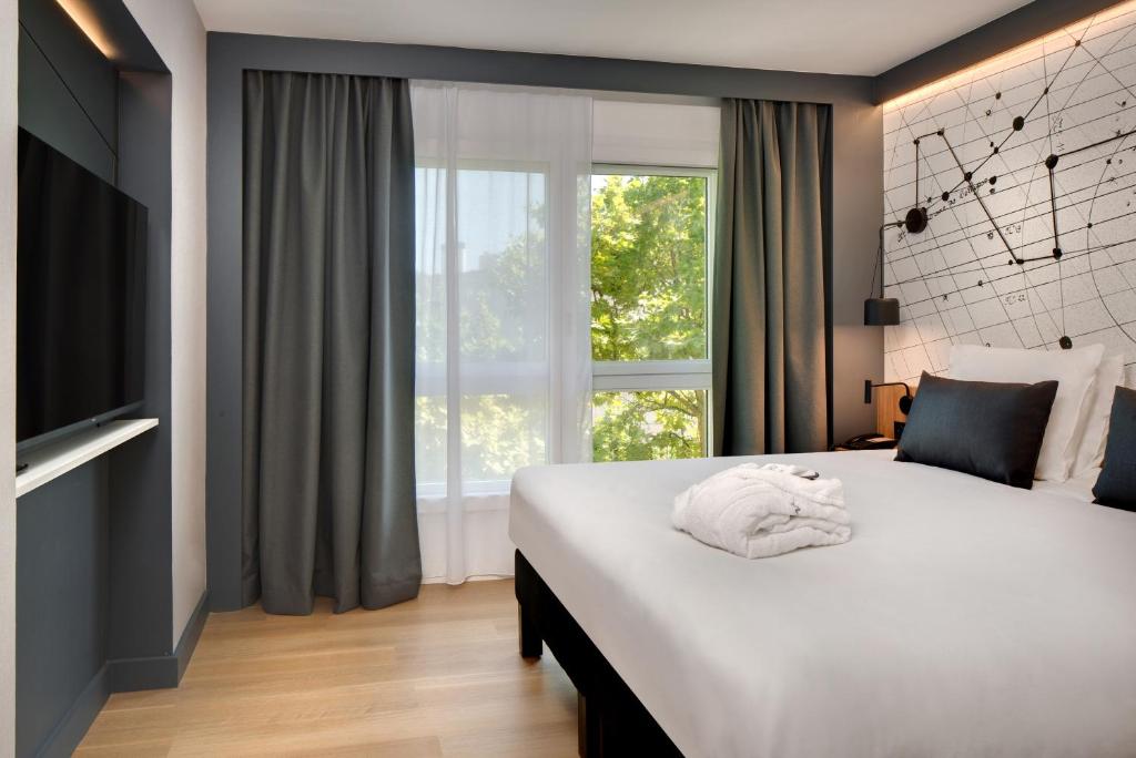 une chambre avec un grand lit blanc avec une fenêtre dans l'établissement Mercure Montpellier Centre Antigone, à Montpellier
