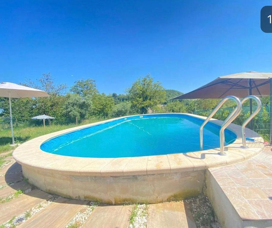 a large swimming pool with an umbrella at Sun Sonia casa in Sarnano