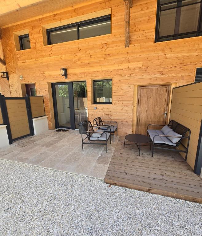 a patio with chairs and tables in front of a wooden building at Gites des ammonites 2 in Montalieu-Vercieu
