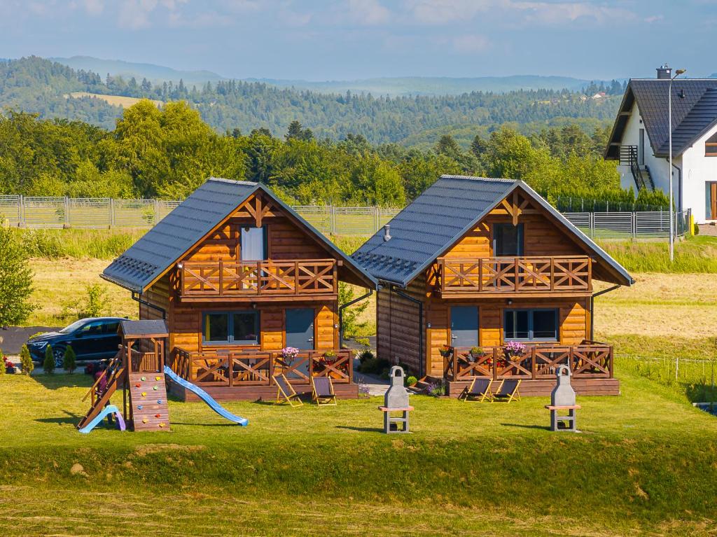 a log cabin with a slide and a playground at Domki w Blasku Słońca in Polańczyk