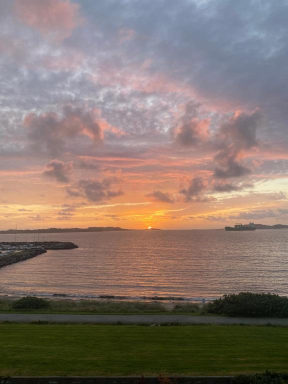 un tramonto sull'acqua con una nave in lontananza di Flott leilighet med fantastisk utsikt a Stavanger