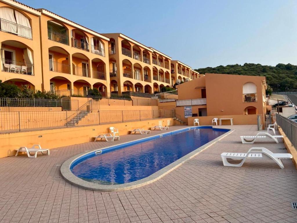 a hotel with a swimming pool in front of a building at LA FRISAIA Appartamento vista mare L4 in Isola Rossa