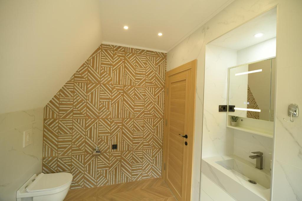 a bathroom with a toilet and a geometric tile wall at Monte zone in Žabljak