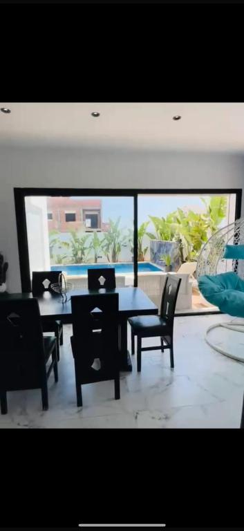 a dining room with a table and chairs and a large window at Villa Solara in Kelibia
