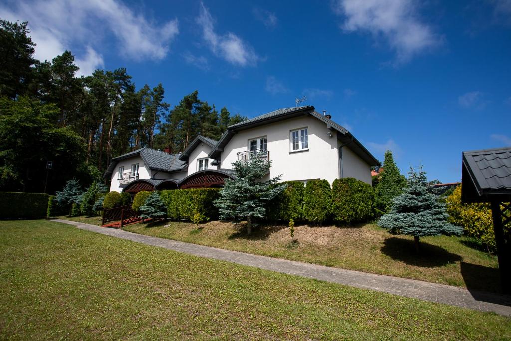 a white house with trees in a yard at Promyk Dębiny in Debina