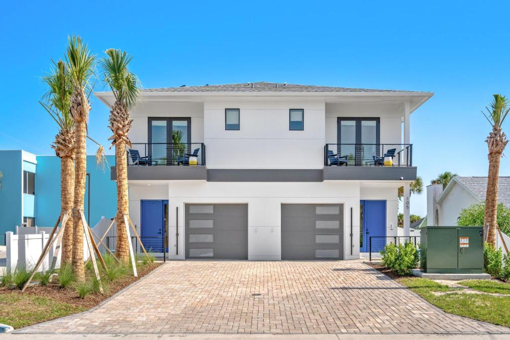 a house with palm trees in front of it at Wave Haven Villas - 2 Luxury Villas - 3BR 3 and a Half BA Each - Sleeps 8 Per Unit - Hot Tub - Across from Beach - Rocket and Beach Views in Cocoa Beach