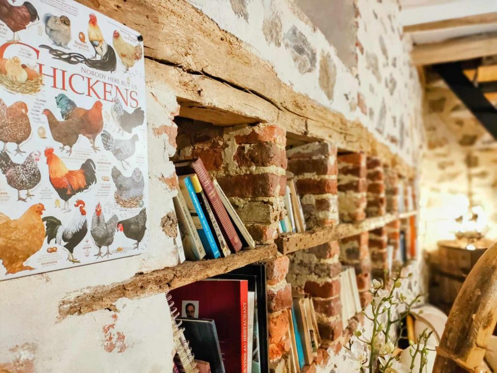 una pared de ladrillo con un estante con libros en La Source de nos Racines, Gîte de caractère, en Beaufort
