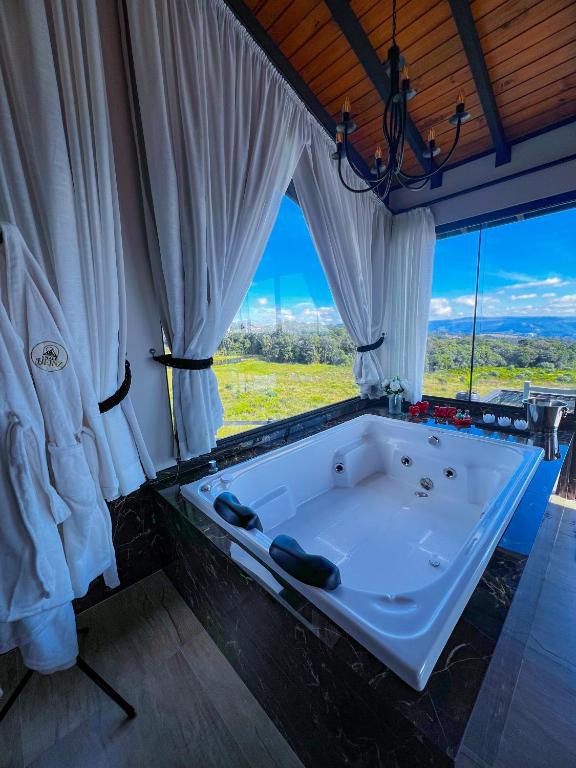 a large tub in a room with a large window at Chalé Heinz in Rancho Queimado