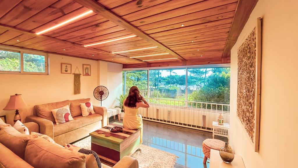 a woman standing in a living room looking out a window at Pine Beach House Alleppey in Alleppey