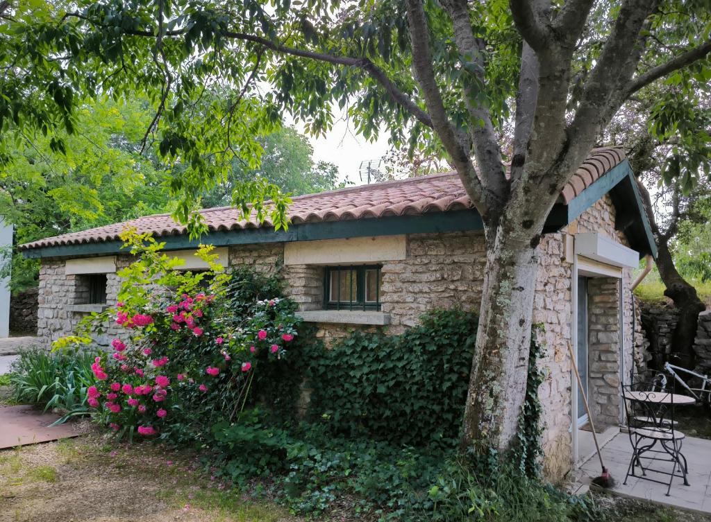 una piccola casa in pietra con un albero e fiori di Havre champêtre en ville de Nîmes a Nîmes