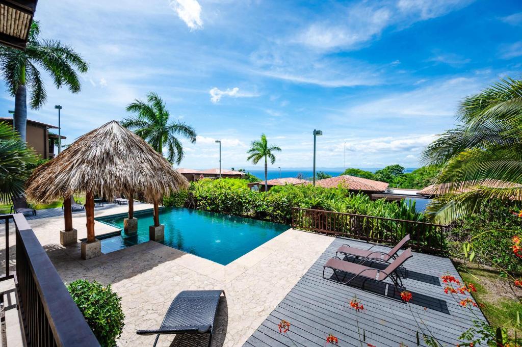 a swimming pool with two chairs and a umbrella at Rooftop Pool & Ocean Views, Sunset BBQ in Ocotal