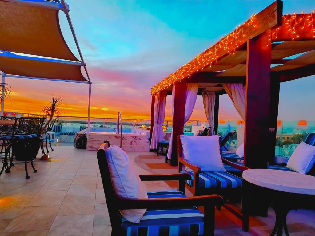 a deck with tables and chairs and a sunset at Hotel HBlue Centro in La Paz