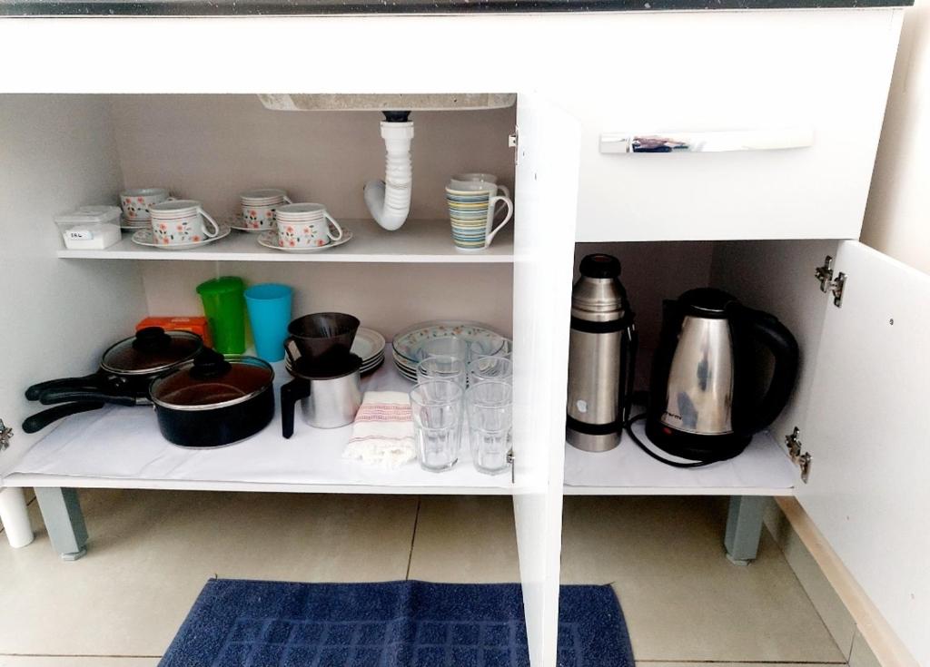 un armario blanco con tazas y platos. en Quarto Privativo Cataratas, en Foz do Iguaçu