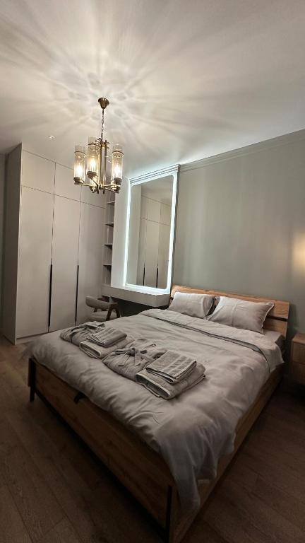 a bedroom with a bed with a mirror and a chandelier at NEXPO Apartment Бизнес-класс in Astana
