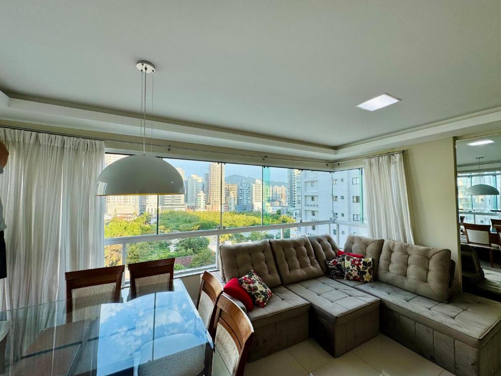 Una sala de estar con un sofá y una ventana grande. en Lindo Apartamento compartilhado vista MAR, en Itapema