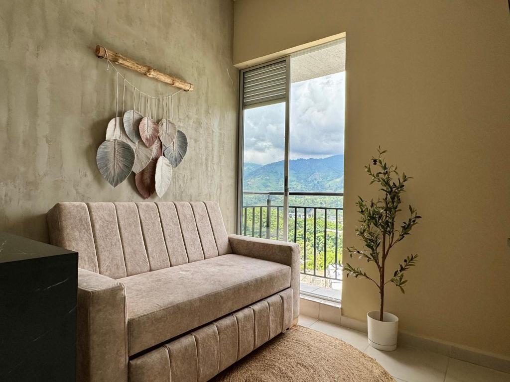 Una sala de estar con un sofá y una ventana grande. en Alojamiento Moderno con Parking privado y Ubicación Privilegiada, en Armenia