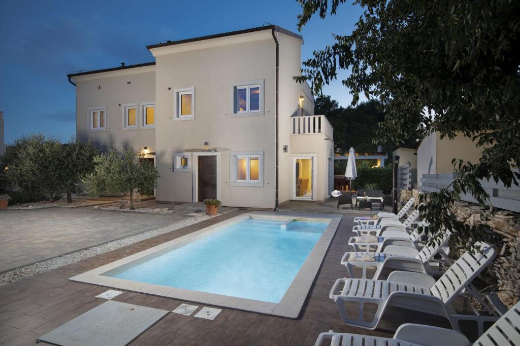 a house with a swimming pool and lounge chairs at Villa Nocciola with Sea View, Private Pool and Sauna in Premantura
