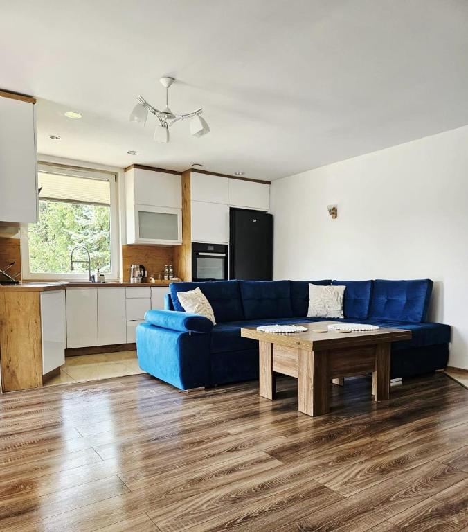 a living room with a blue couch and a table at Domek Zacisze Myśli in Elblag