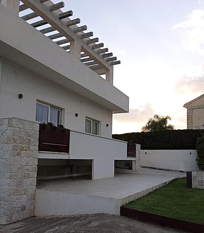 a white house with a porch and a stairway at Salacia rooms in Avola