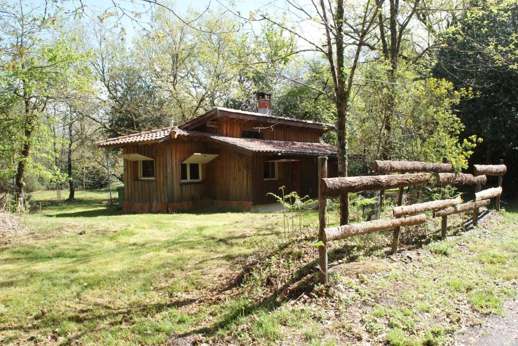 a wooden cabin in a field with a fence at La Palombière in Saint-Symphorien