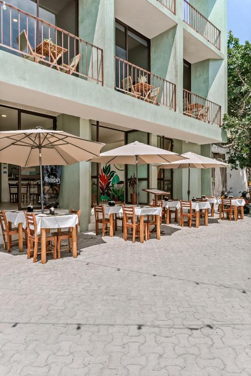 a patio with tables and umbrellas in front of a building at Florita 39 Boutique Hotel Breakfast & Beach Club Included in Isla Mujeres