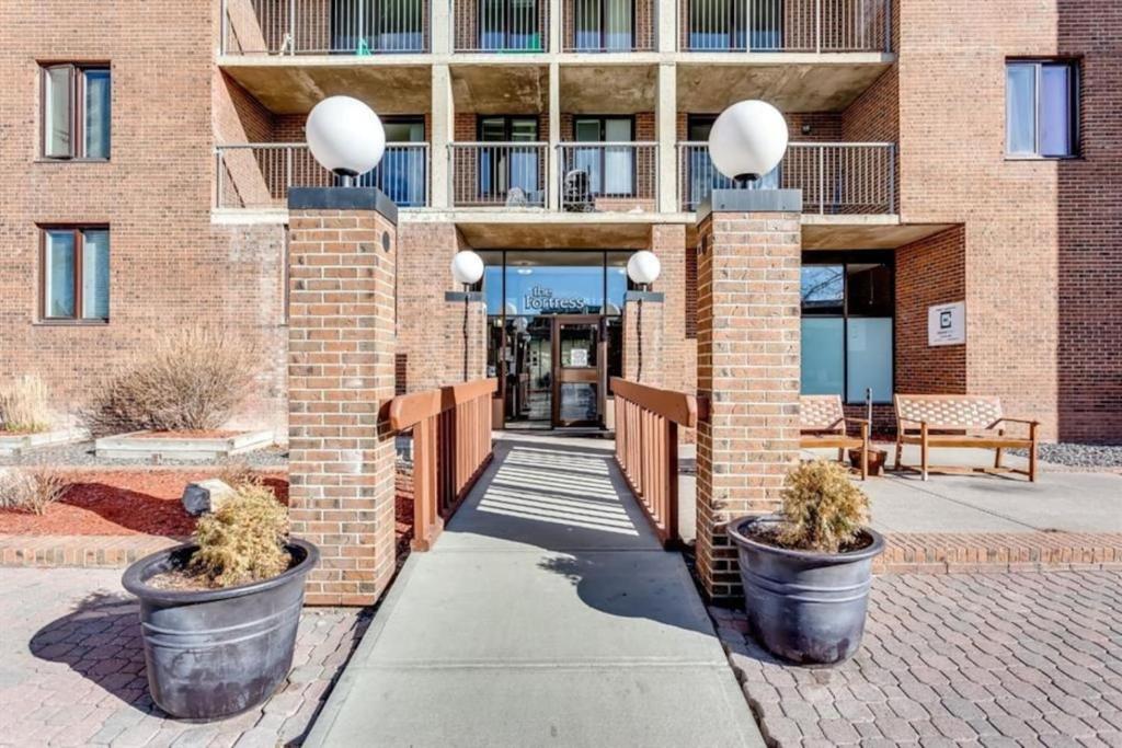 カルガリーにある2-Storey Condo in The Fortress with Pool, Gym, WiFi, Parkingのレンガ造りの建物とその前に置かれた2つの大きな鉢植え