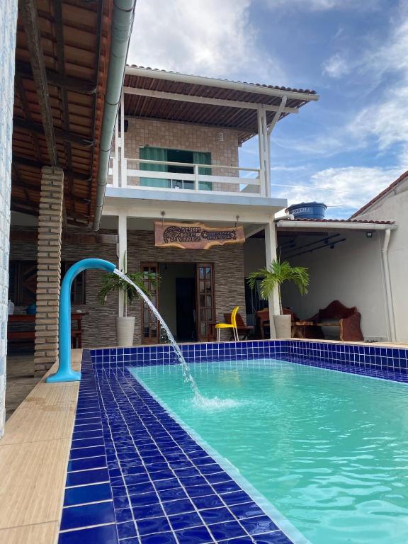 a swimming pool with a water fountain in front of a house at Casa em Marechal Deodoro in Marechal Deodoro
