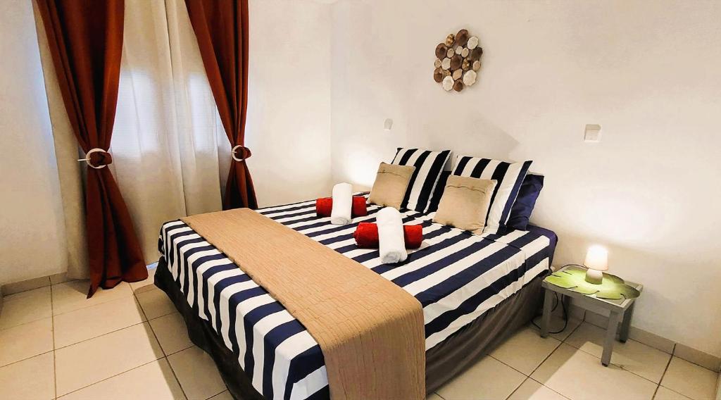 a bedroom with a striped bed with two candles on it at KANEL - Votre havre de paix à lAnse Mitan in Les Trois-Îlets