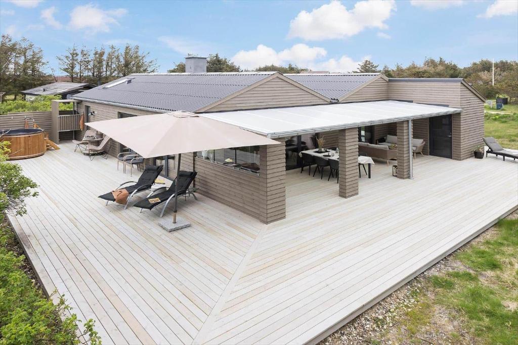 a wooden deck with an umbrella and tables and chairs at 157-Thisted-Isfuglevej-17 in Thisted