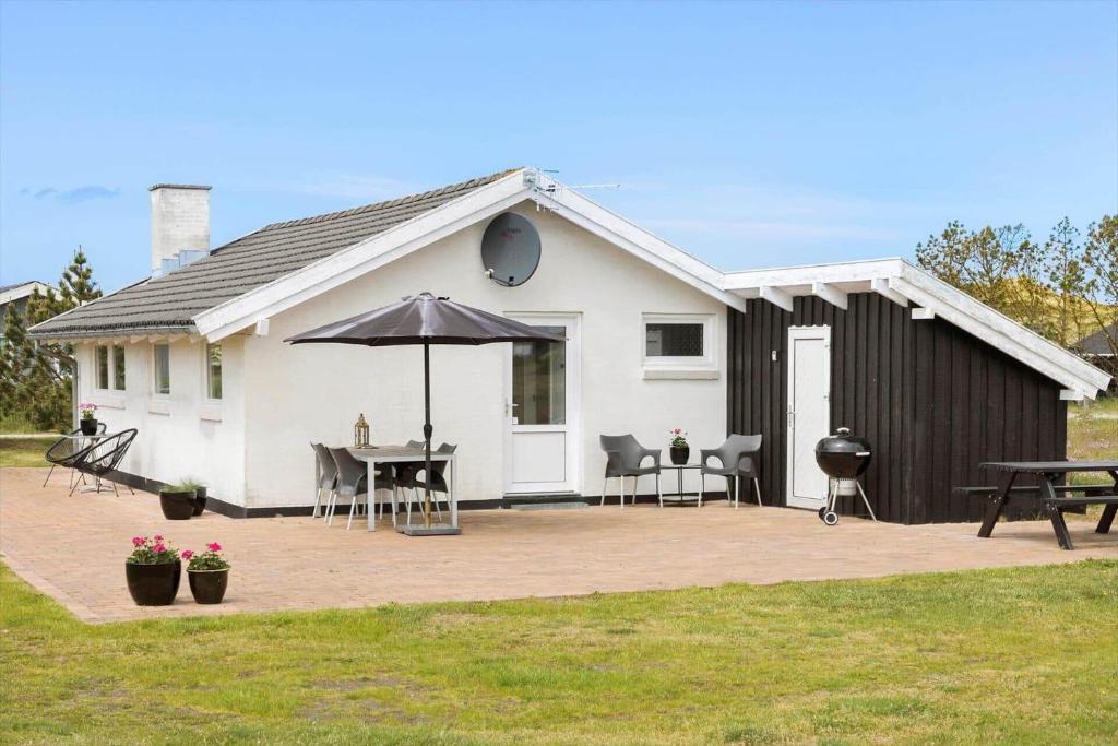 ein weißes Haus mit einem Tisch und einem Regenschirm in der Unterkunft 760 Thisted - Pighvarvej 30 in Thisted