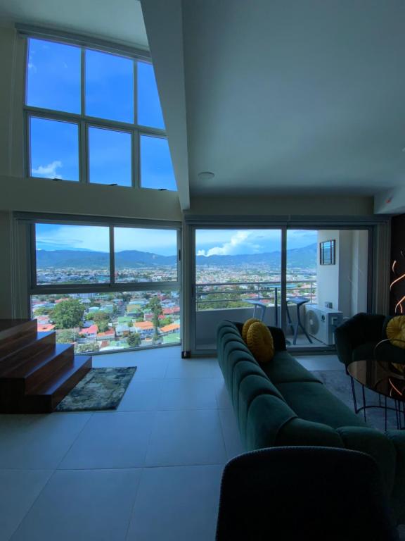 a living room with a couch and large windows at Exclusive apartment in downtown Costa Rica in San José