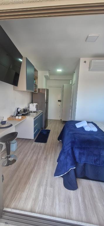 a bedroom with a blue bed and a kitchen at Studio Metrô Tatuapé Wi-fi-Piscina-Academia in Sao Paulo