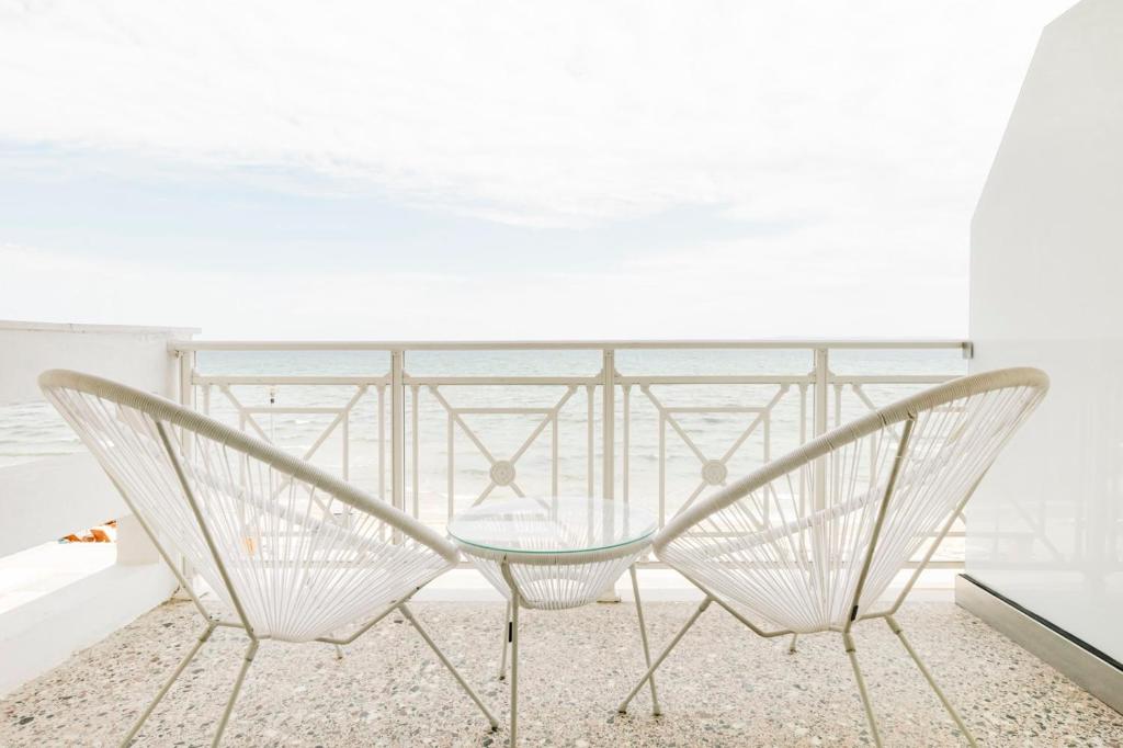 two chairs and a glass table on a balcony at Manda Ray Seafront Apartment Endless Blue View in Perea