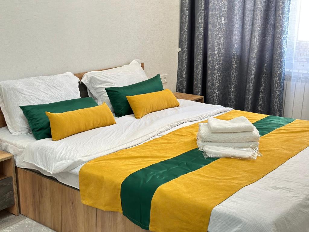 a large bed with green and white pillows and a yellow blanket at Duet in Bishkek