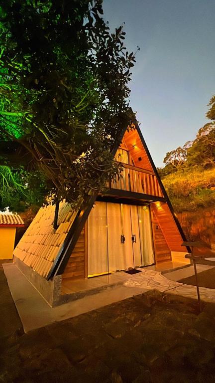 a small house with two doors and a tree at Chalé Bela Vista in Munhoz