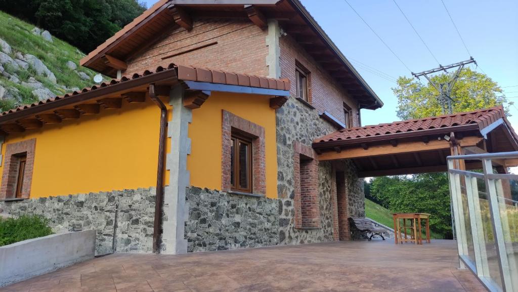 a house with a yellow wall and a patio at EL PICO Casa en plena naturaleza con vistas espectaculares in Arredondo