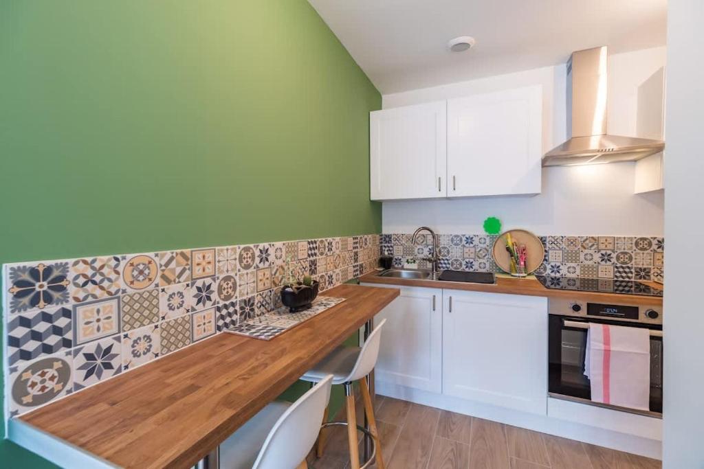a kitchen with white cabinets and tiles on the wall at Le T2 Zen de Guingamp confort au coeur de la ville in Guingamp