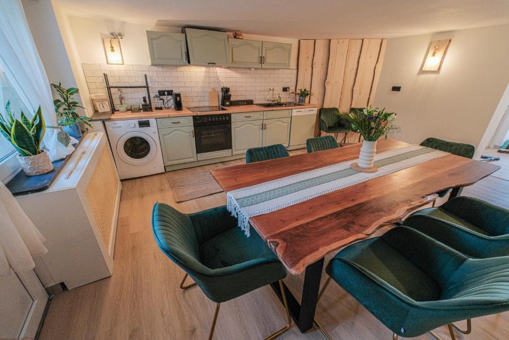 a kitchen with a wooden table and green chairs at Alpino STAY Geräumige Ferienwohnung am Alpsee mit Garten in Immenstadt im Allgäu